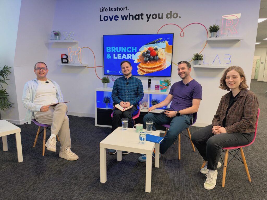 Yordan Dimitrov with three other people seated in a semicircle in front of a screen reading "Brunch & Learn", smiling towards the camera
