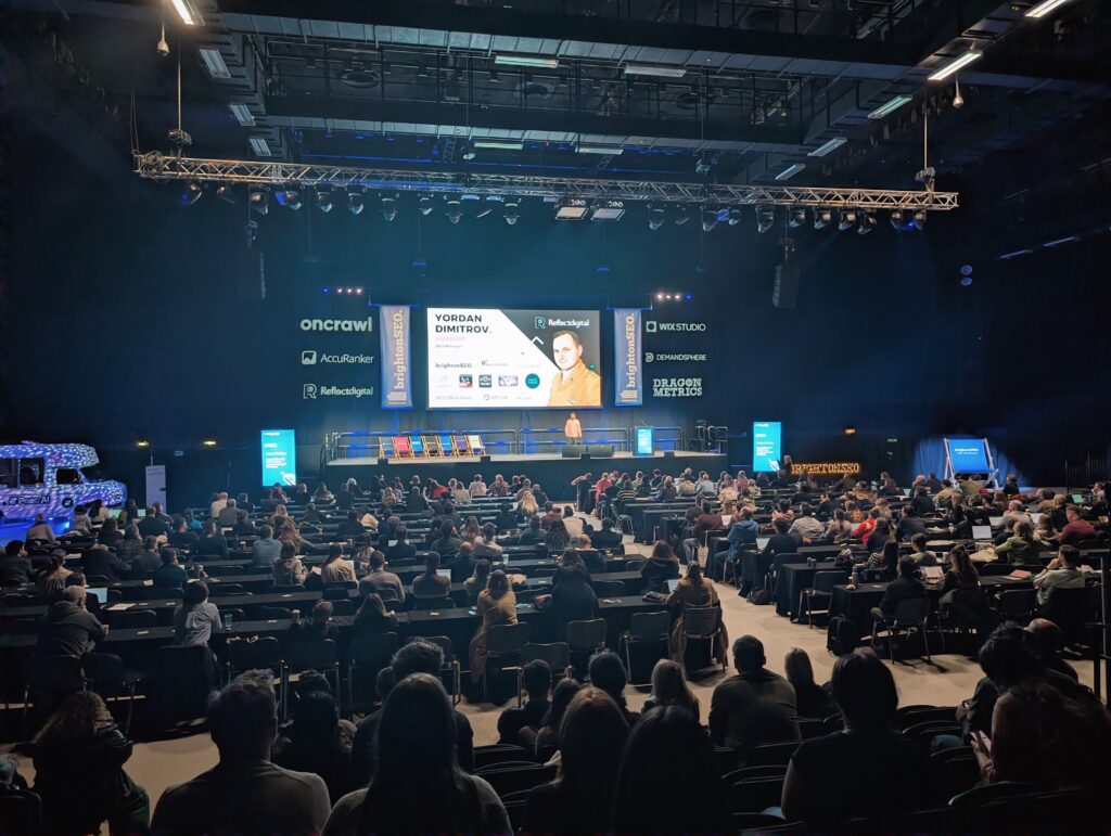 Yordan Dimitrov presenting on a large stage, with a seated audience in the foreground