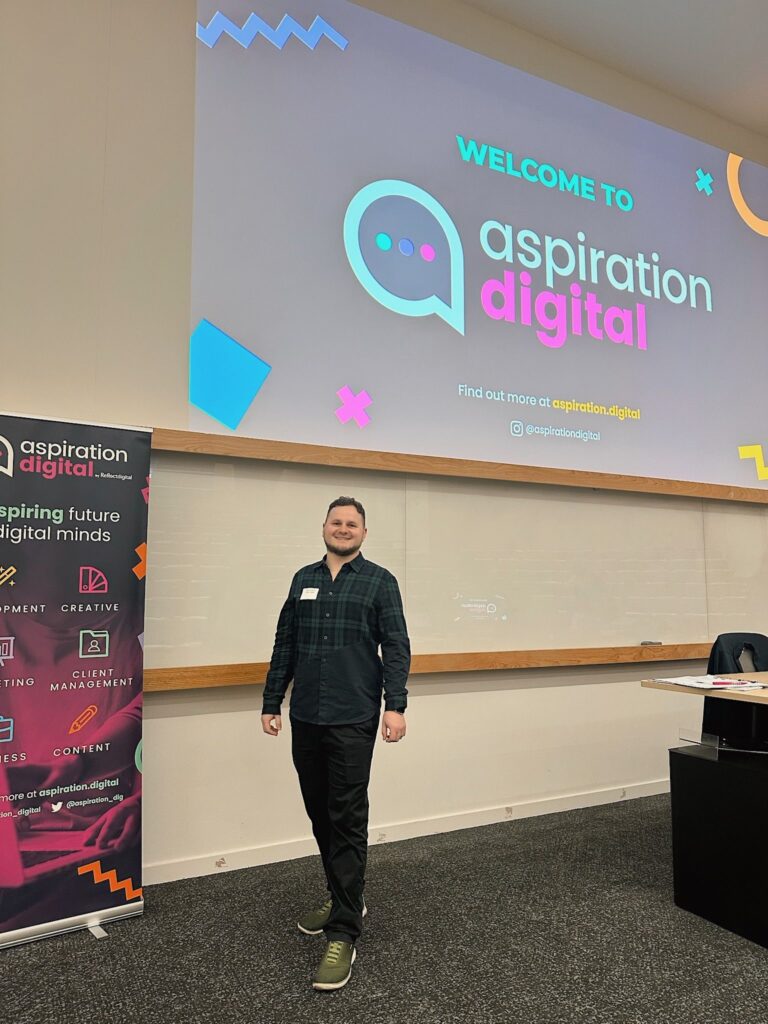 Yordan Dimitrov standing in front of a welcome slide for Aspiration Digital, next to a roll-up banner