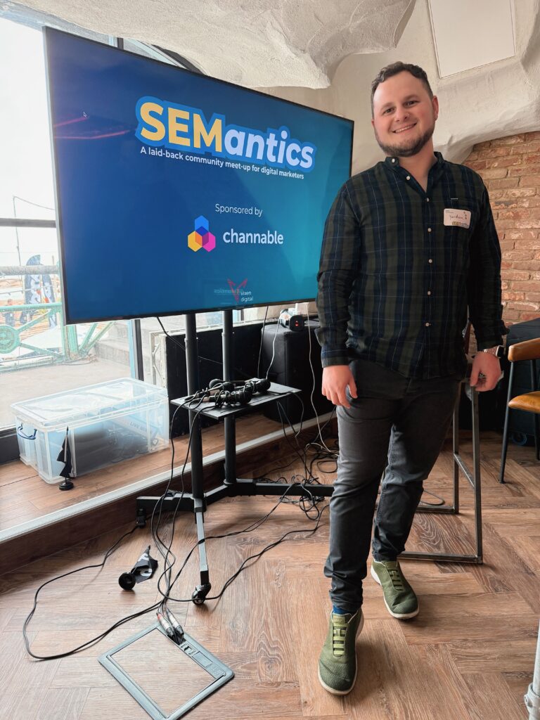 Yordan Dimitrov standing beside a large screen showing the SEMantics logo